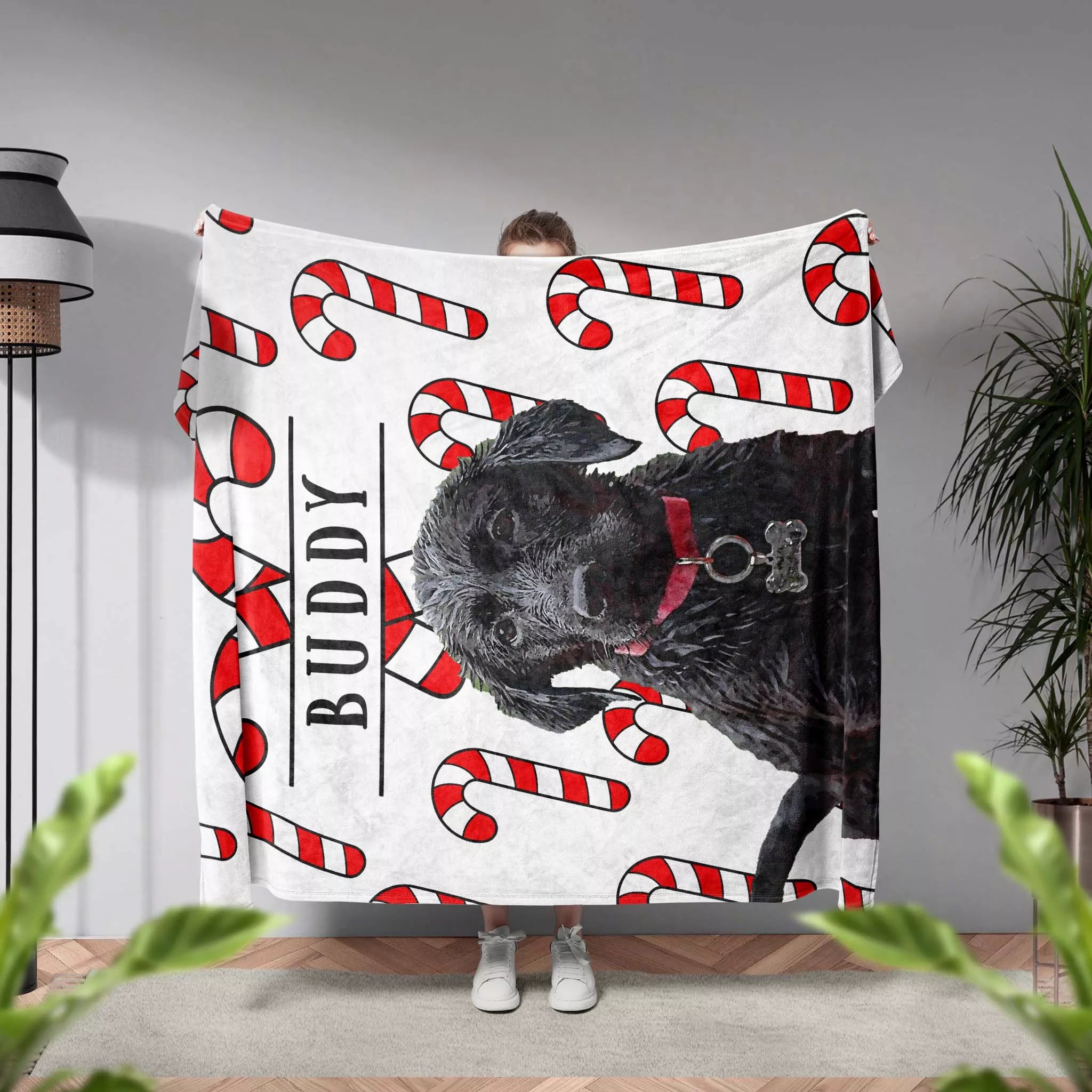 Person holding a blanket with a Black Retriever dog and candy canes design, labeled 'Buddy'.