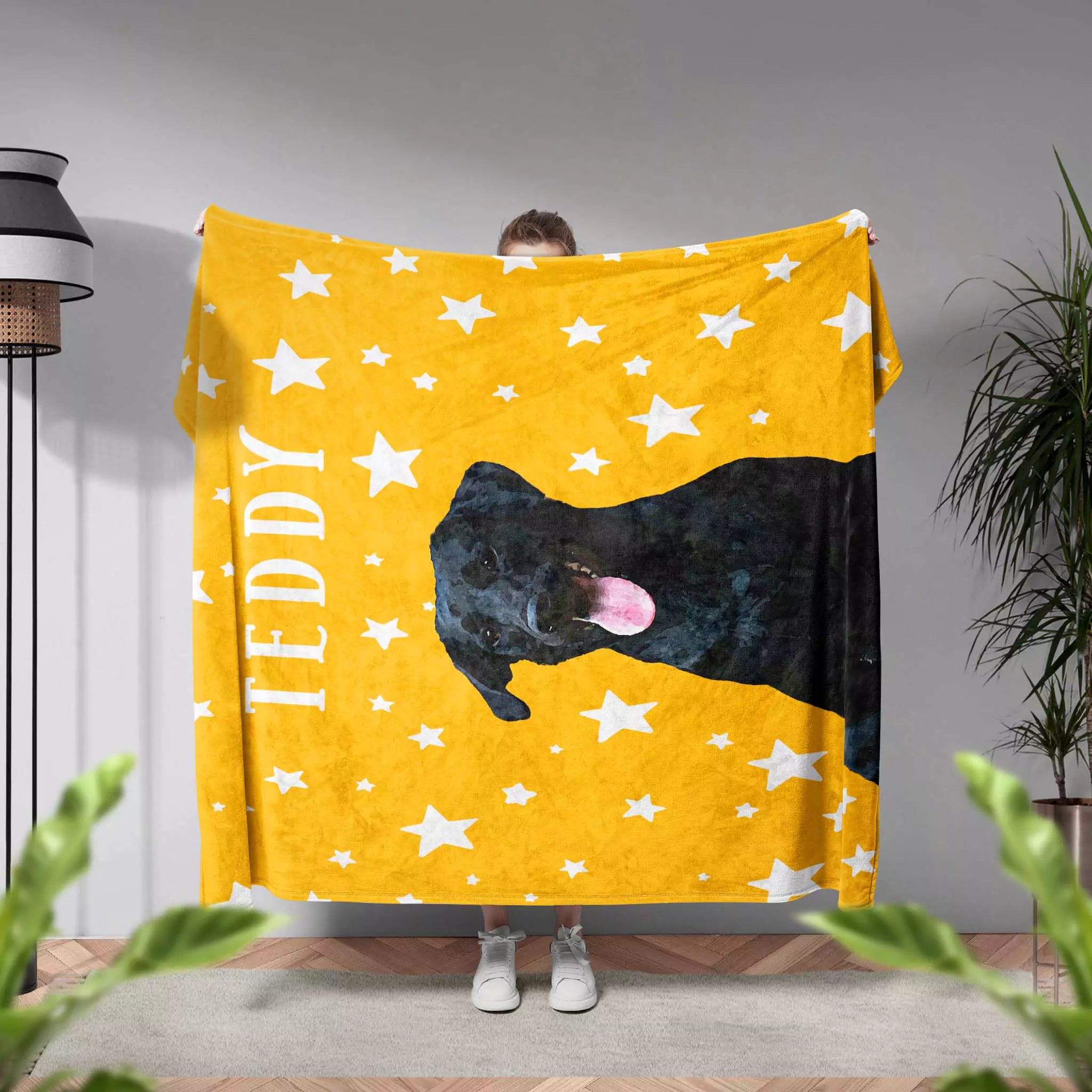 Person holding a yellow dog blanket with a black Labrador dog design and 'TEDDY' custom text.