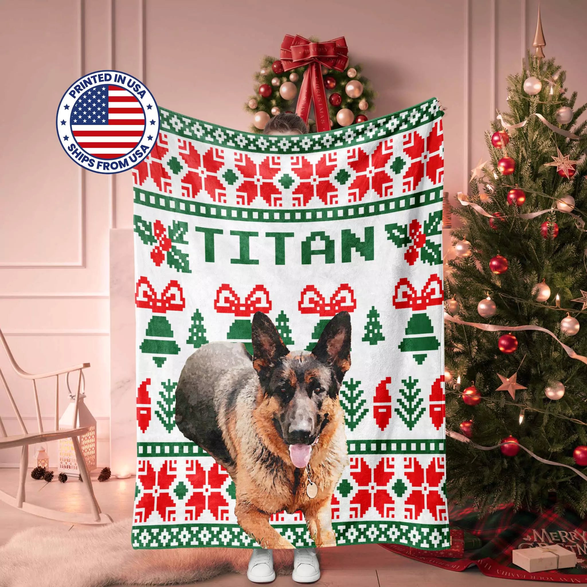 Dog standing on a Christmas-themed ugly sweater blanket with 'TITAN' printed on it, surrounded by a decorated Christmas tree and wreath.