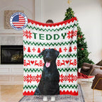 Person holding a Christmas ugly sweater blanket with a dog's face on it, in a living room setting.