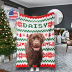 Christmas-themed dog blanket with a dog's face printed on it, held by a person in a living room.