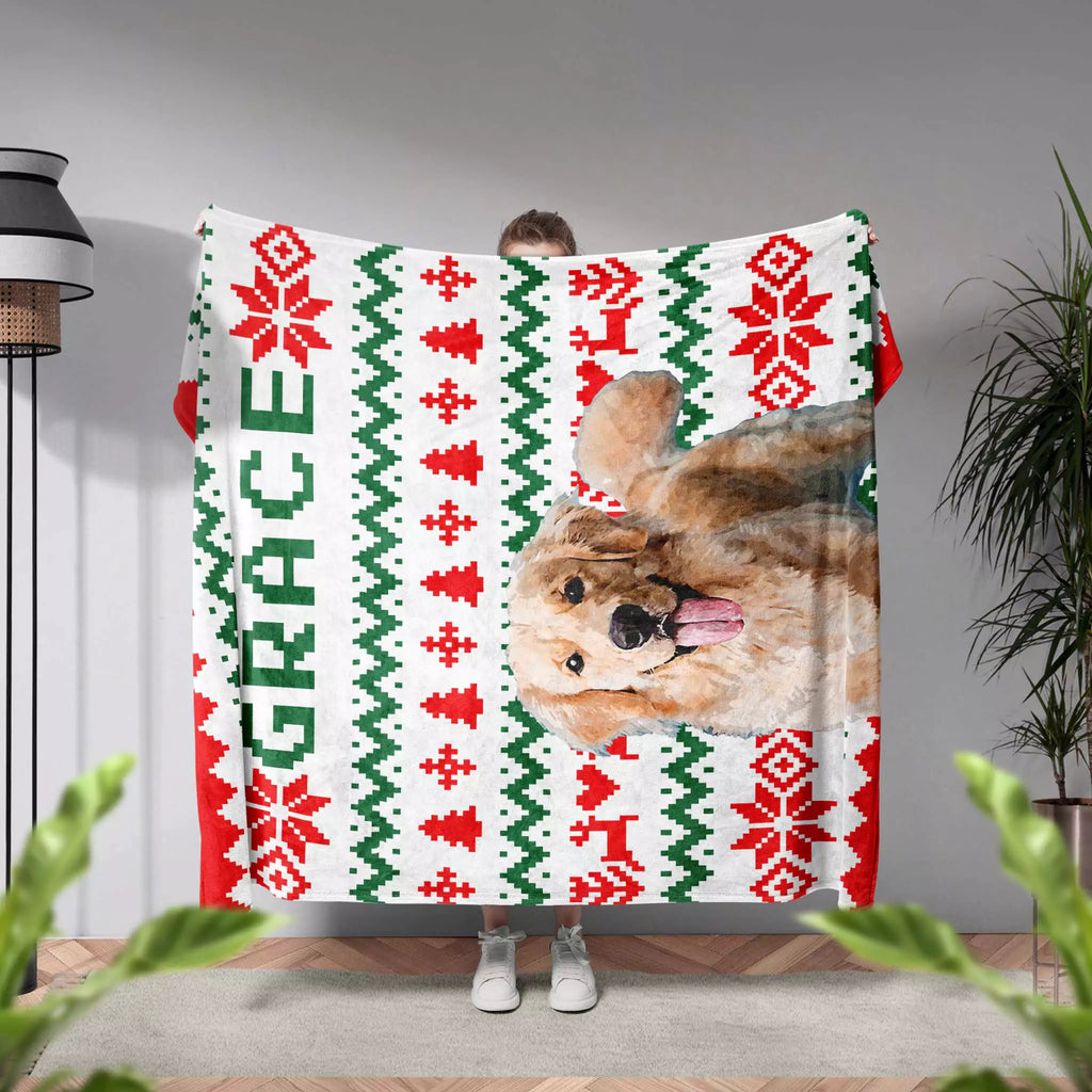 Person holding a ugly sweater Christmas-themed blanket with a dog's face and the name 'Grace'.