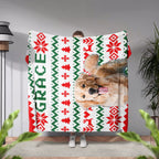 Person holding a ugly sweater Christmas-themed blanket with a dog's face and the name 'Grace'.