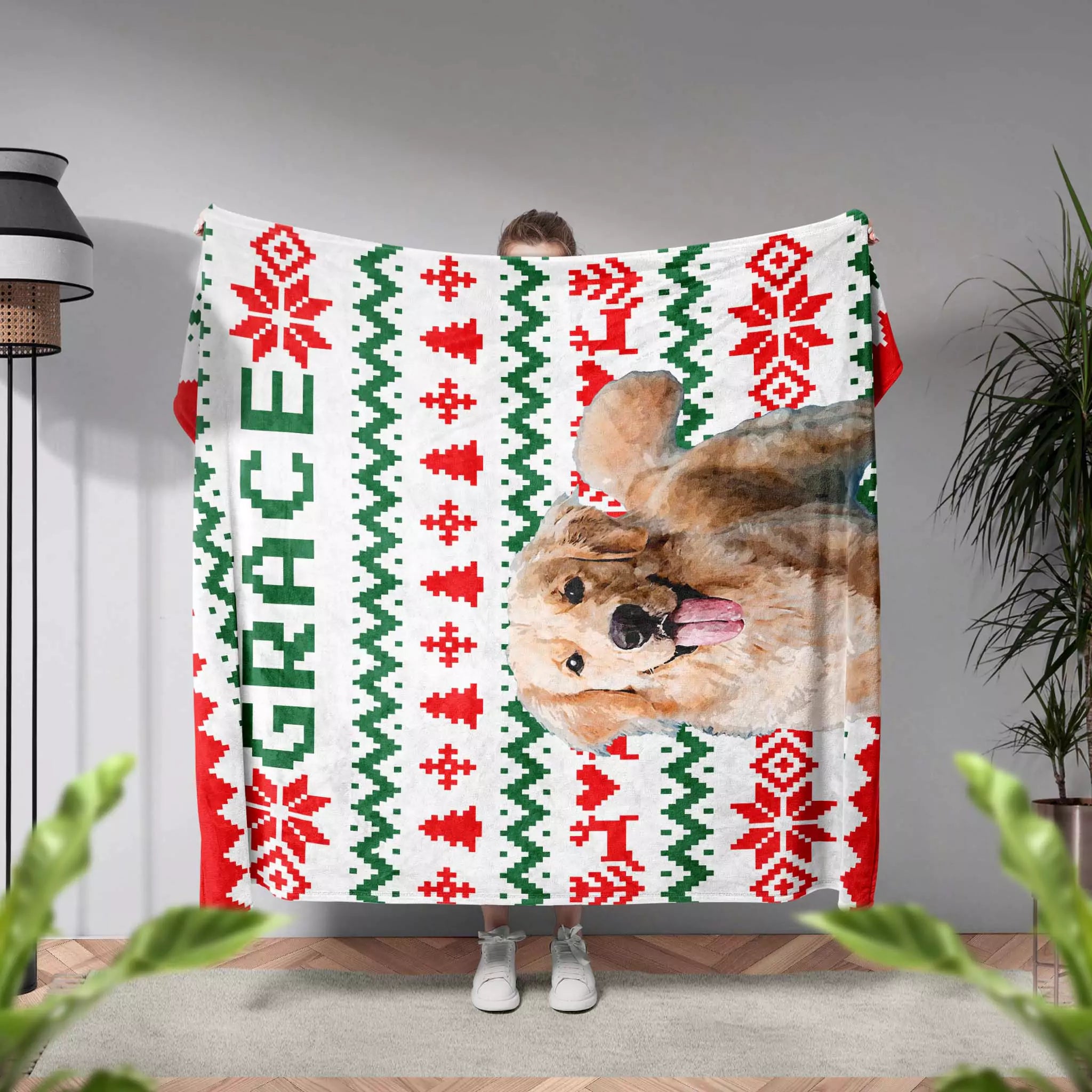 Person holding a ugly sweater Christmas-themed blanket with a dog's face and the name 'Grace'.