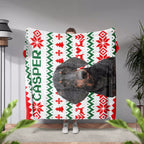 Person holding an ugly sweater Christmas-themed blanket with a dog's face and 'Casper' text.