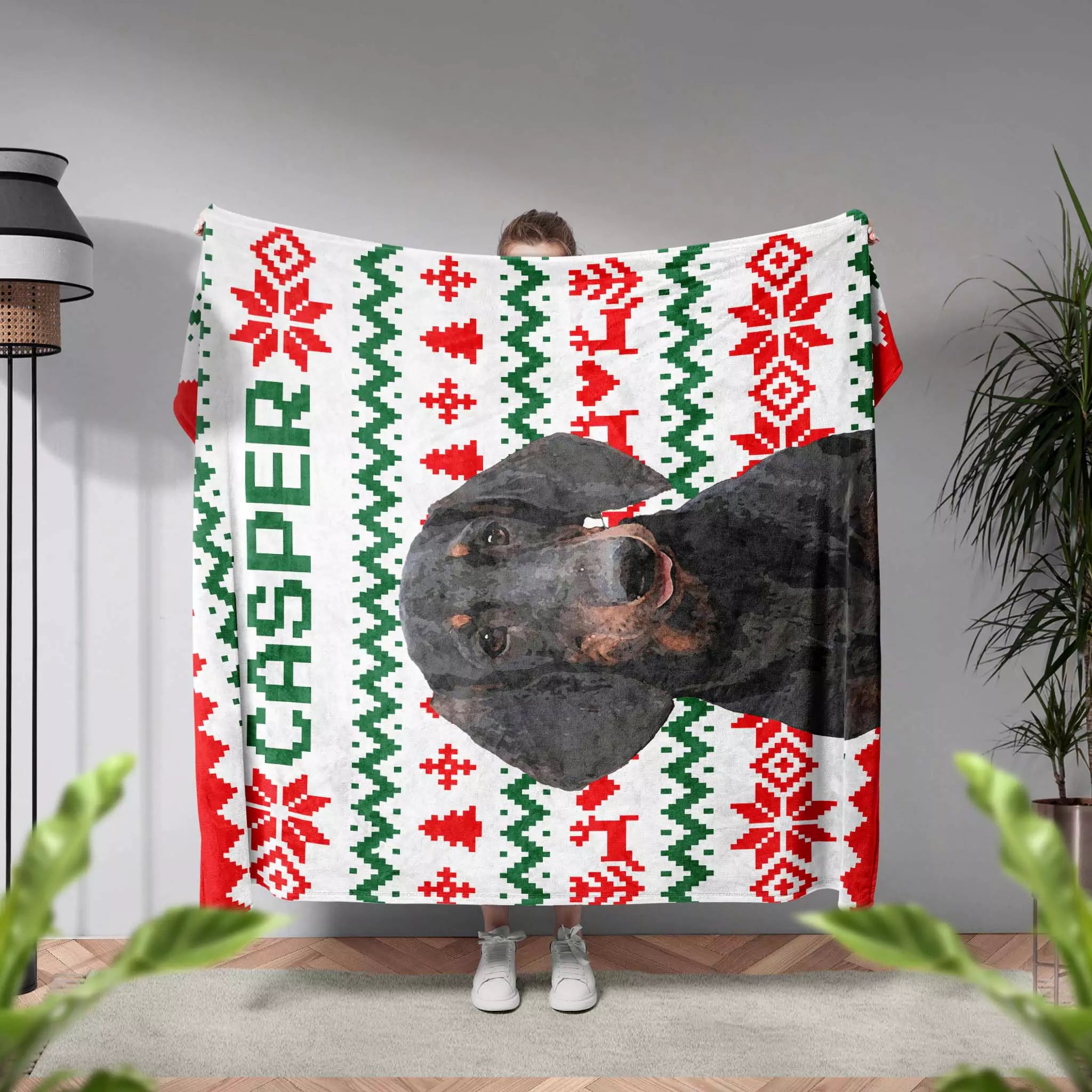 Person holding an ugly sweater Christmas-themed blanket with a dog's face and 'Casper' text.