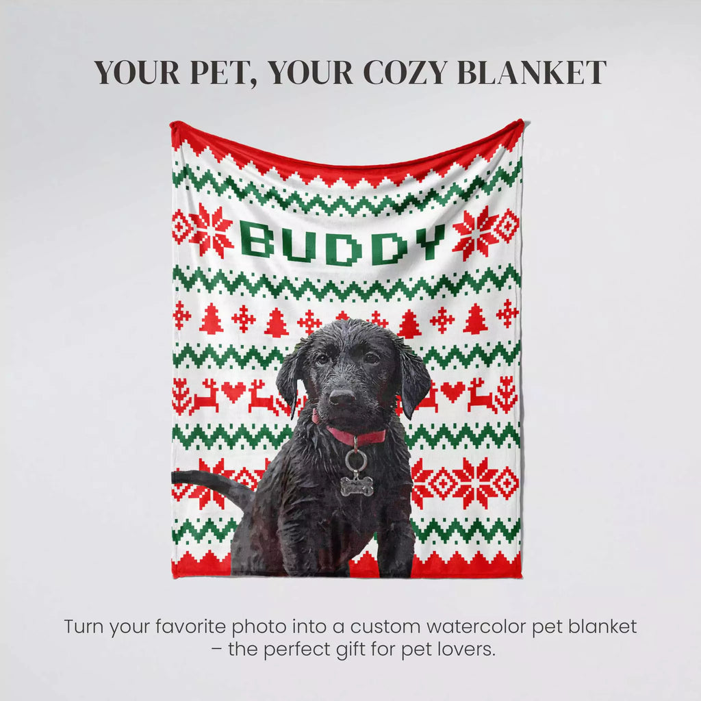 Black Retriever Dog sitting on an ugly sweater red, green, and white patterned blanket with 'Buddy' written on it.