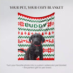 Black Retriever Dog sitting on an ugly sweater red, green, and white patterned blanket with 'Buddy' written on it.